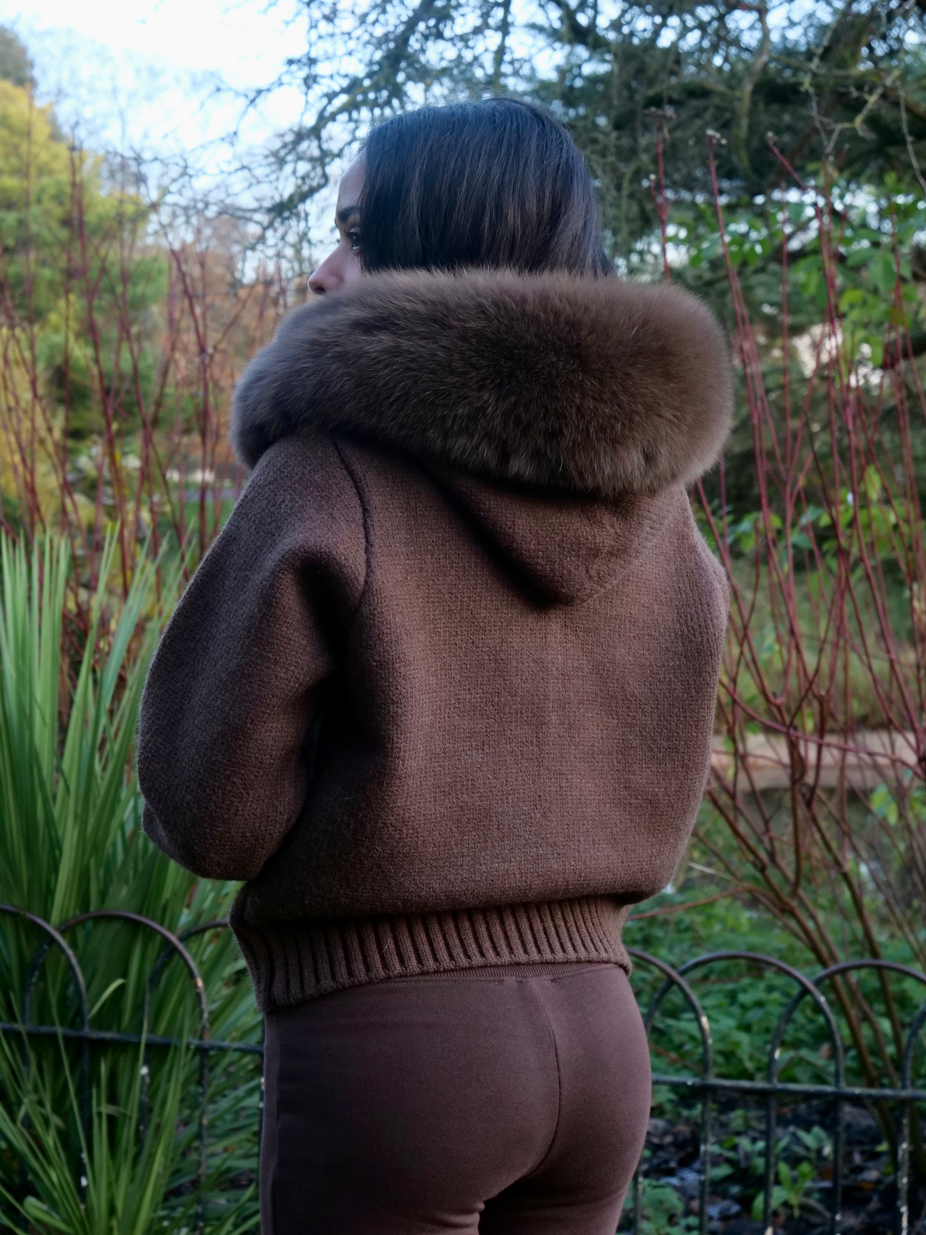Person wearing a brown coat with a fur hood in an outdoor setting