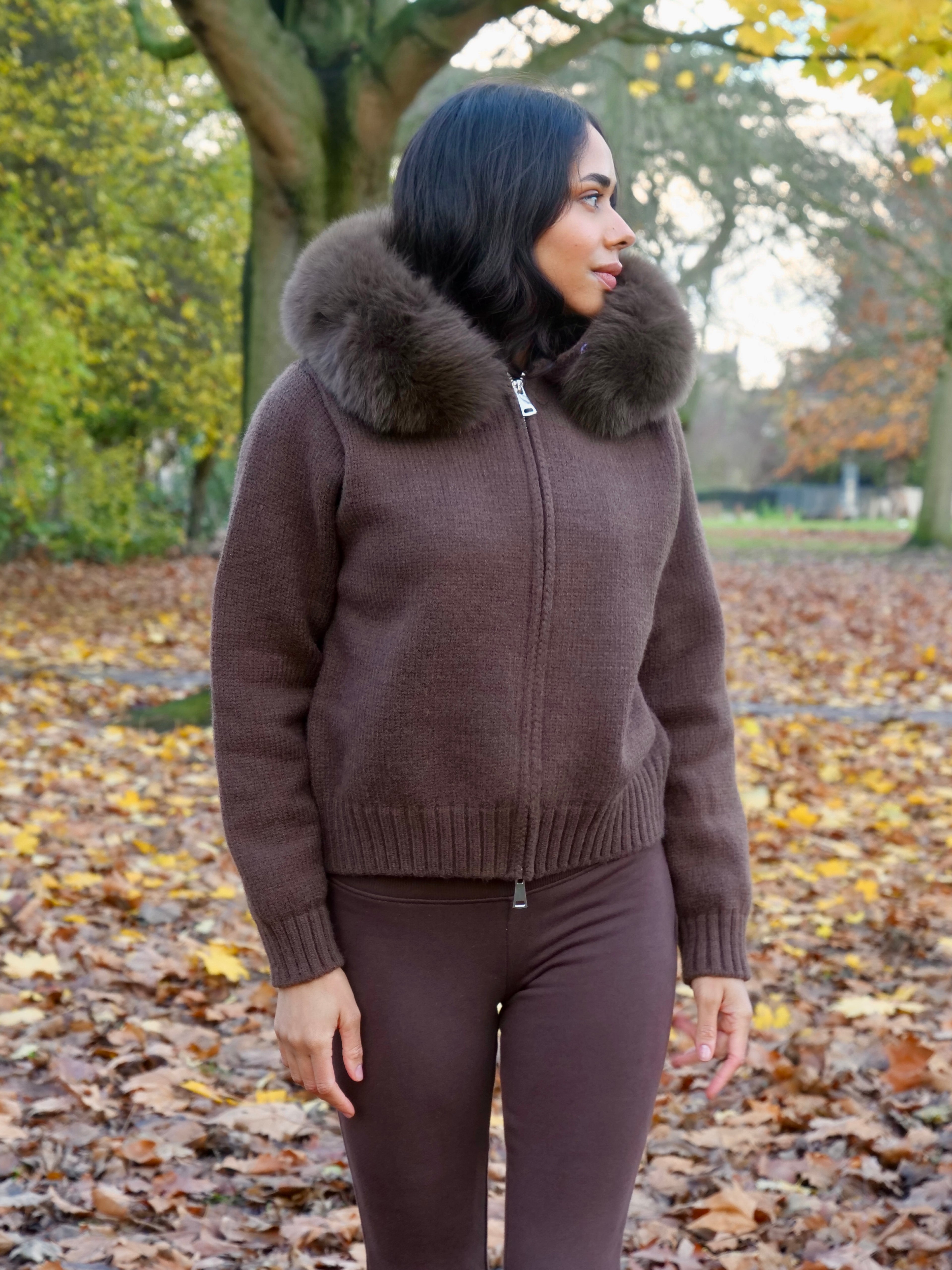 Woman wearing a brown sweater with a fur collar in an autumn park.