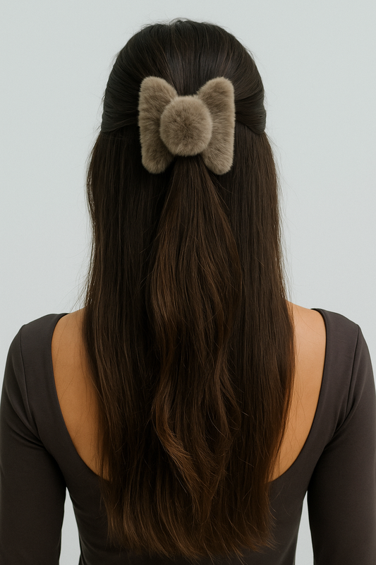 Person with long hair wearing a fluffy brown hair bow against a plain background