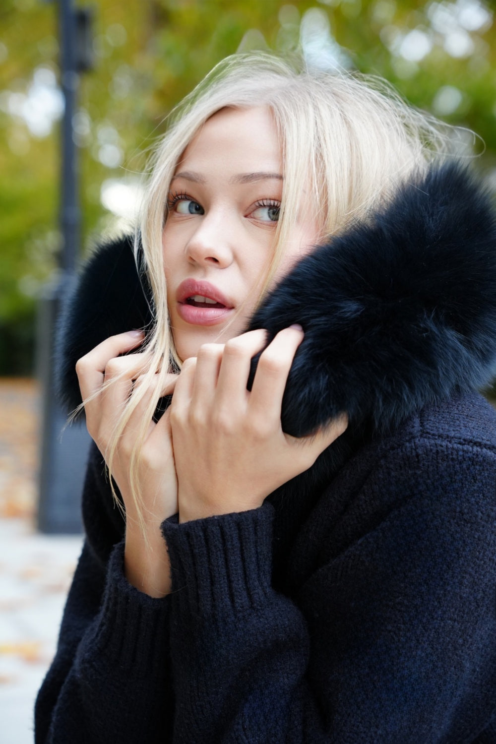 Woman wearing a dark coat with a fur collar outdoors